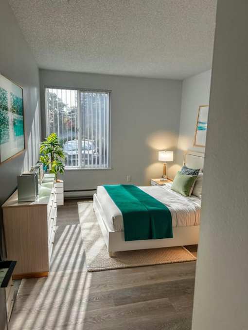 A bedroom with a bed, nightstand, and window.