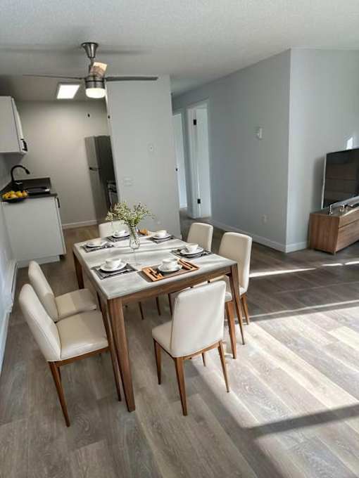 A dining room with a table set for two and a television in the background.