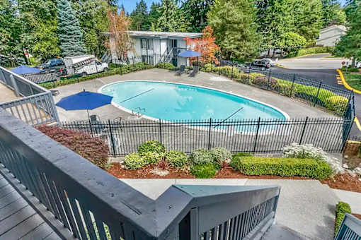 A small pool surrounded by a black fence and a blue umbrella.