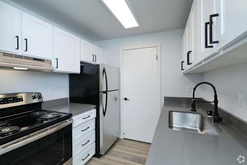 A kitchen with black appliances and white cabinets.