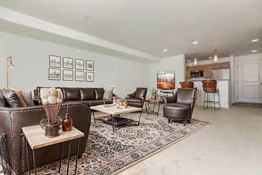 A living room with a brown leather couch and a rug.