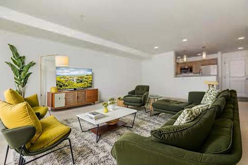 A living room with a green couch, yellow chair, and a television.