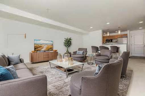A living room with grey couches and a painting on the wall.