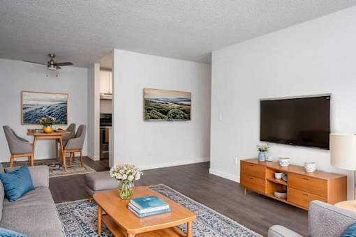 A living room with a grey couch, a wooden coffee table, a flat screen TV, and a painting on the wall.
