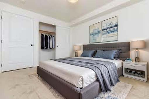 A bedroom with a bed, nightstand, and a painting on the wall.