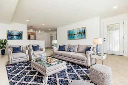 A living room with a white couch, a glass coffee table, and a blue rug.