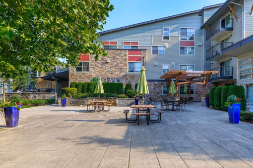 a patio with tables and umbrellas in front of an apartment building at Delano, Washington, 98052