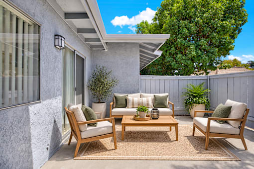 Outdoor patio with wooden furniture and privacy fence at Coventry Square Apartments, Upland