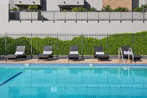 A pool with chairs and a fence.