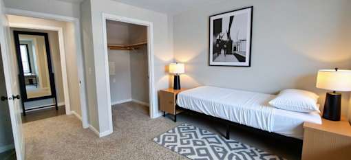 A bedroom with a bed, two lamps, and a framed picture on the wall.