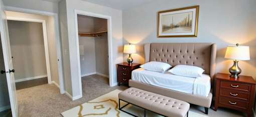 A bedroom with a bed, nightstands, and a painting on the wall.