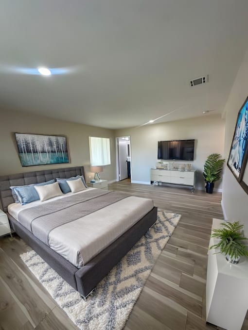 A bedroom with a large bed and a painting on the wall.