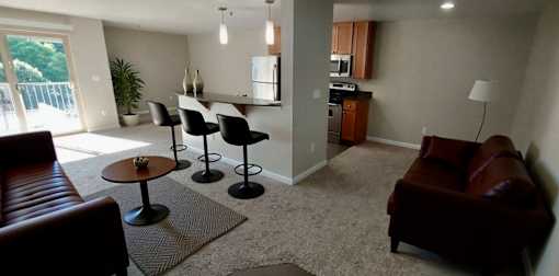 A living room with a brown couch and a table with chairs.