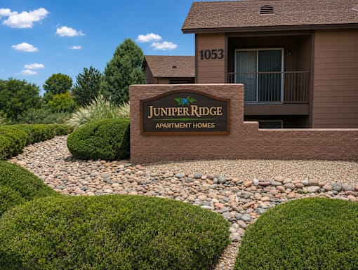 A brown building with a sign that says Juniper Ridge Apartment Homes.
