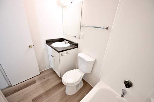 A white toilet with a black counter top in a small bathroom.