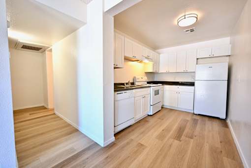 A kitchen with white appliances and wooden floors.