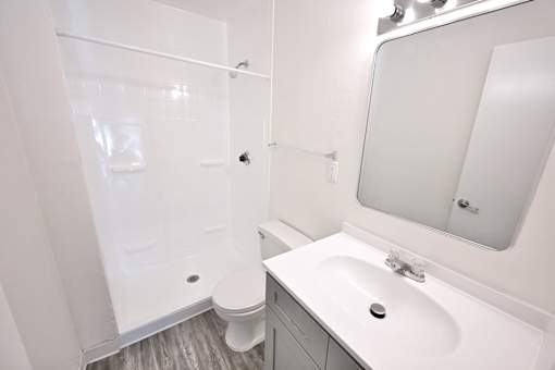 A white bathroom with a toilet, sink, and shower.