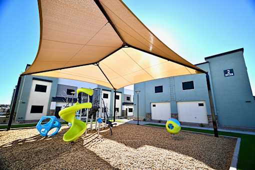 A playground with a yellow canopy and a blue and yellow slide.