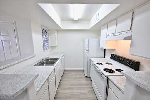 A white kitchen with a stove, sink, and refrigerator.
