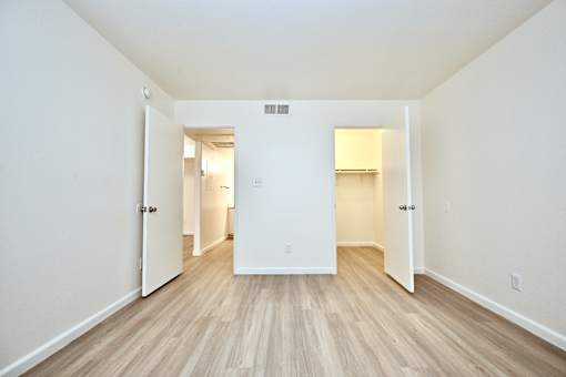 A long hallway with white walls and wood floors.