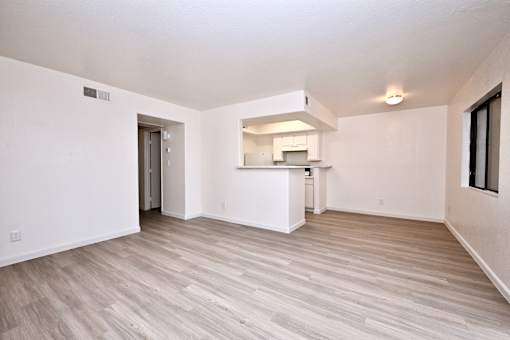 A spacious room with a kitchenette and wood flooring.