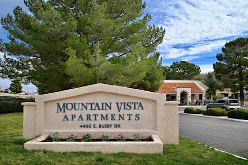 A sign for Mountain Vista Apartments is in front of a tree.