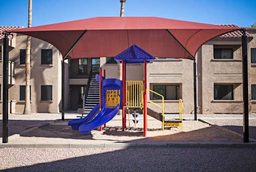 A playground with a red canopy and a blue slide.