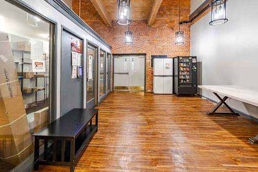 A long hallway with a bench and a fridge.