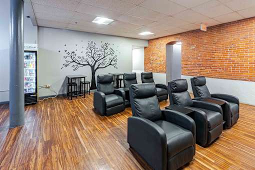 A room with black leather chairs and a tree mural on the wall.