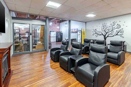 A room with black leather chairs and a wooden floor.