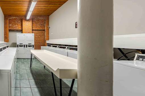 A long white table is in the middle of a room with brick walls.