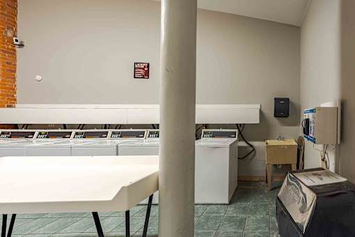 A white table is in the foreground of a room with a washing machine and dryer in the background.