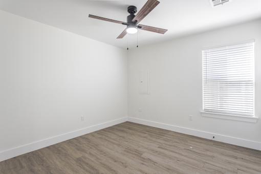 A room with a ceiling fan and a window with blinds.