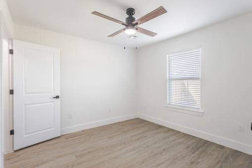 A room with a ceiling fan and a window with blinds.