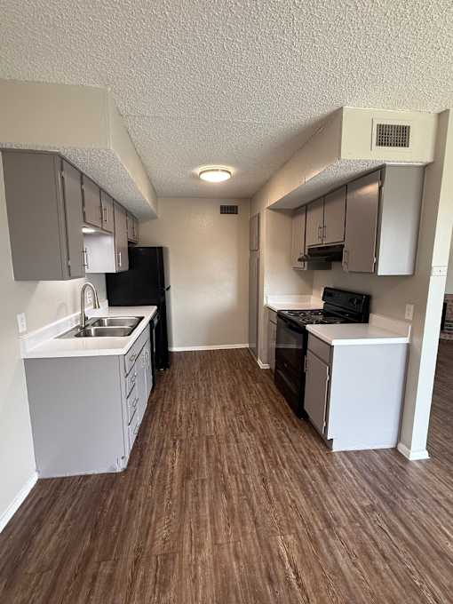 A kitchen with white cabinets and a black fridge.