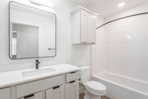 A white bathroom with a sink, toilet, and bathtub.