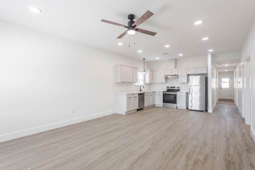 A spacious kitchen with a ceiling fan and wooden flooring.