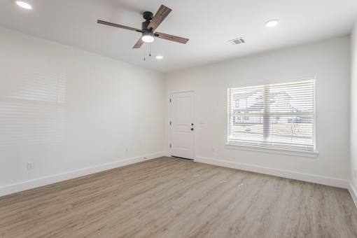 A room with a ceiling fan and a window with blinds.