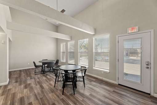 A room with a table and chairs and a door with an exit sign.