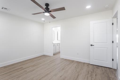 A room with a ceiling fan and light fixture, a door, and a window with a white frame.