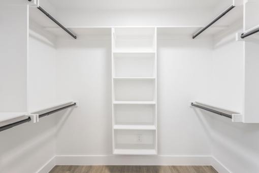 A white walk-in closet with shelves and a bench.
