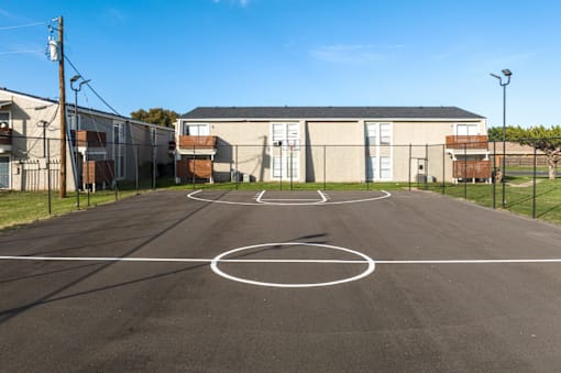 A basketball court is located in the middle of a parking lot.