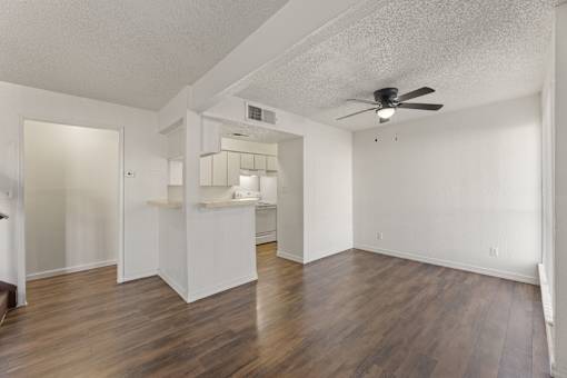 A room with a ceiling fan and wooden floors.