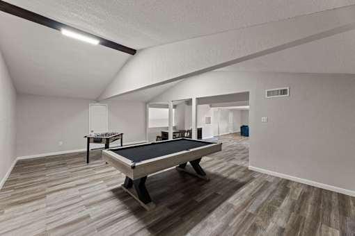 A pool table in a room with wooden flooring.