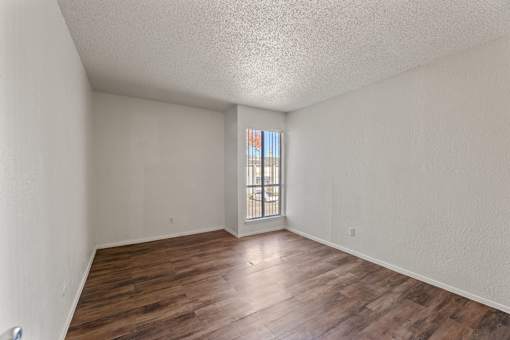 A room with wooden floors and a window with bars on it.