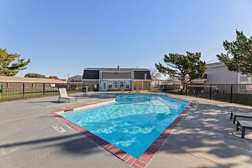A small pool with a red border and a building in the background.