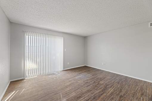 A room with wooden flooring and a window with blinds.