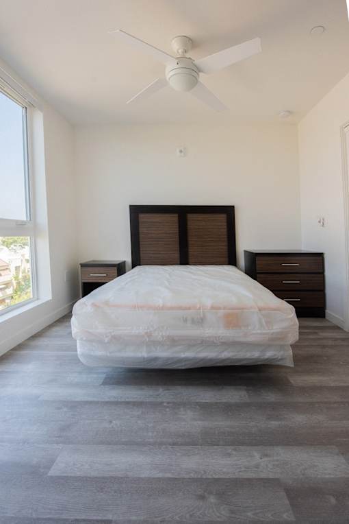 a bedroom with a bed and two dressers and a ceiling fan
