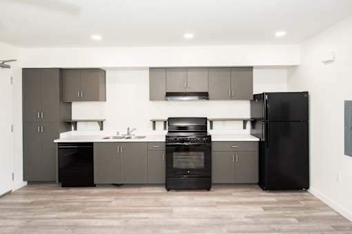 an empty kitchen with black appliances and gray cabinets
