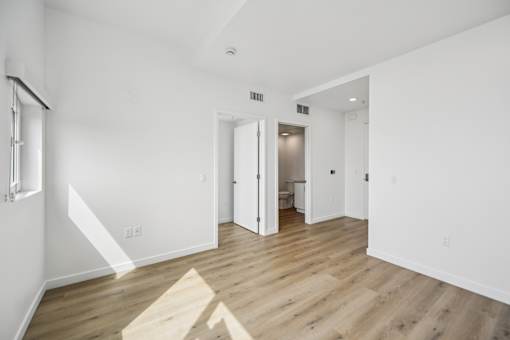 A white room with vinyl flooring and a staircase on the left.